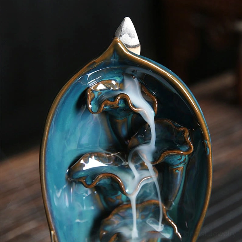 Close-up front view of lotus cavity backflow incense holder with teal glazed lotus interior and gold trim edges showing flowing smoke effect