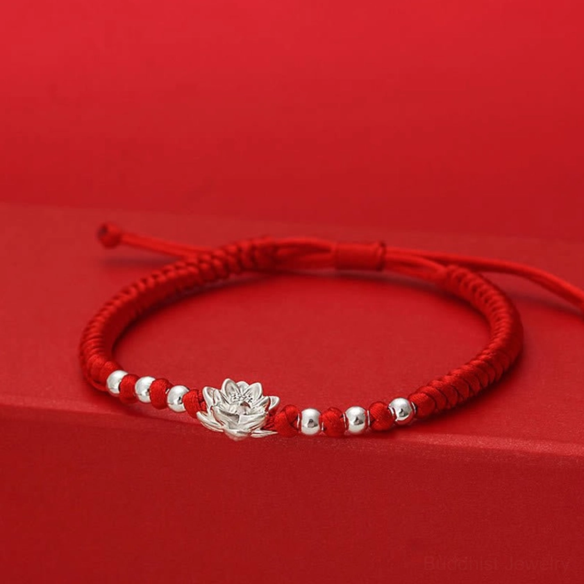 Polished 999 sterling silver lotus pendant and silver bead accents on braided red cord