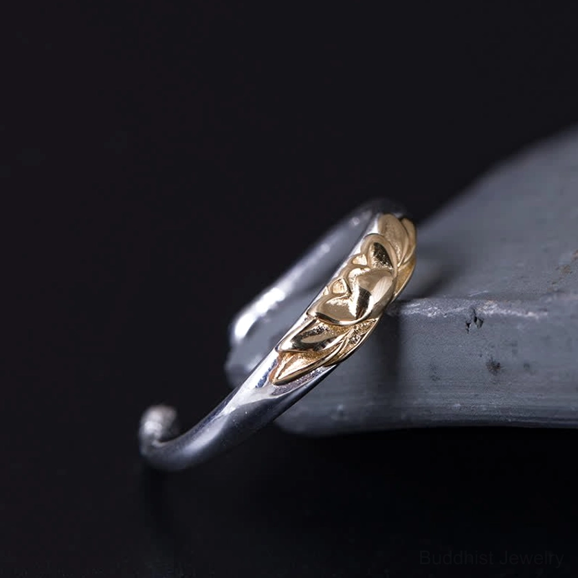 Silver lotus flower ring oblique view displaying embossed gold lotus decoration on curved silver band