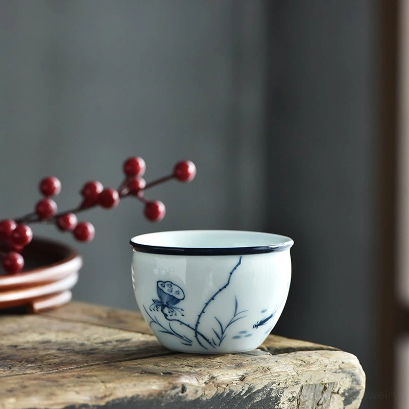 Blue and white porcelain tea cup with delicate lotus and dragonfly pattern, smooth finish elegant design