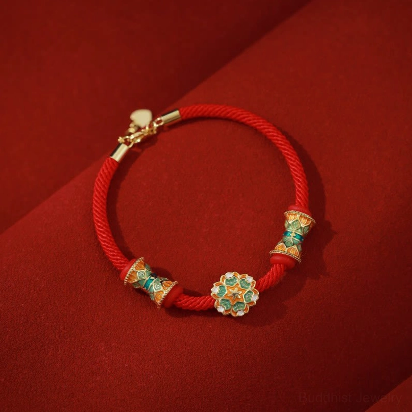 Sterling silver lotus drum charm with red cord bracelet, top-down side view showcasing enamel details on dark velvet