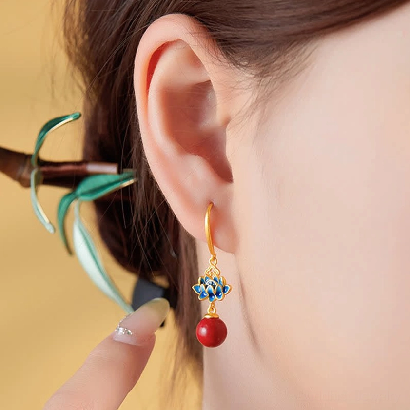 Woman wearing cinnabar lotus drop earrings with decorative gold hairpin - close-up ear wearing shot