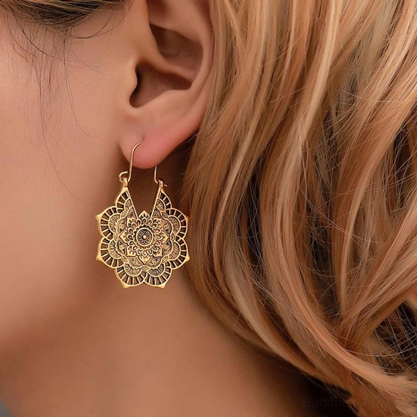 Buddhist lotus drop earrings worn on earlobe, close-up side view showing antique gold carved flower details