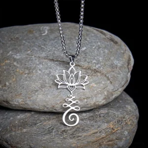 Silver lotus enlightenment pendant necklace with hollow carved Buddhist symbol design, displayed from top-down angle on grey stones