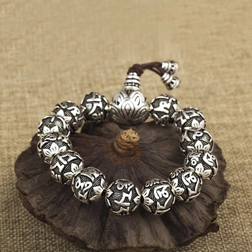 Lotus-carved guru bead mala bracelet with dark brown cord and fully engraved mantra beads on wooden coaster
