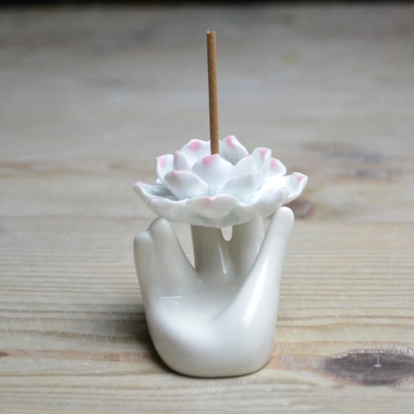 Front direct view of white ceramic lotus hand incense holder showing detailed pink petal tips and upright incense stick for meditation practice