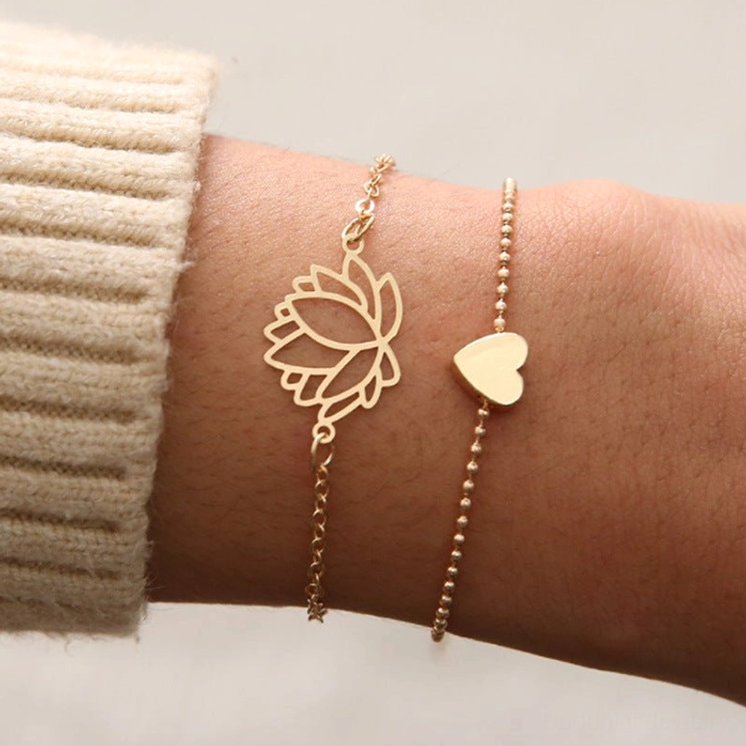 Stackable lotus heart bracelets layered on wrist with knitted sweater showing delicate rose gold design
