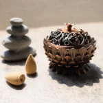 Lotus flower incense burner bronze finish displayed on stone table with stacked rocks and backflow incense cones