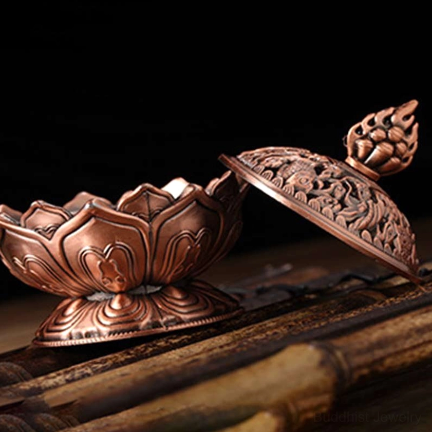 Copper red lotus incense burner detail showing flame-shaped finial on top and carved hollow patterns for waterfall smoke effect