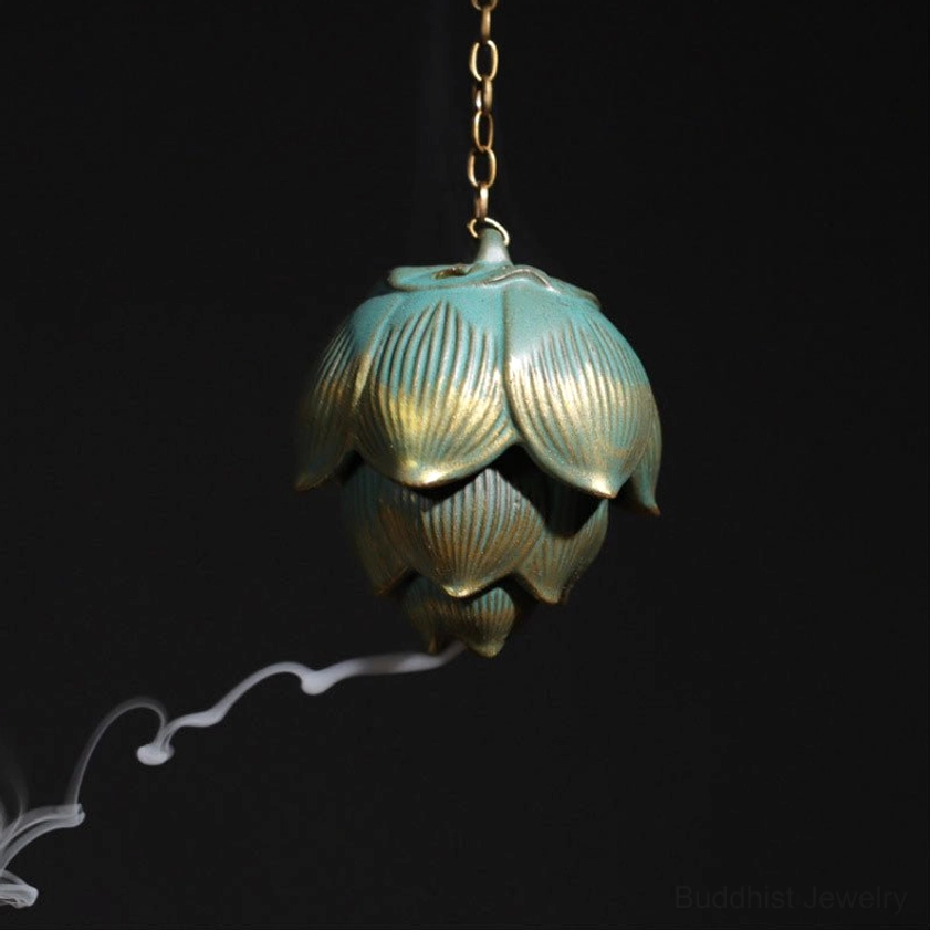 Handcrafted lotus hanging incense burner with green ceramic and gold gilded finish, suspended front view with incense smoke, dark studio background
