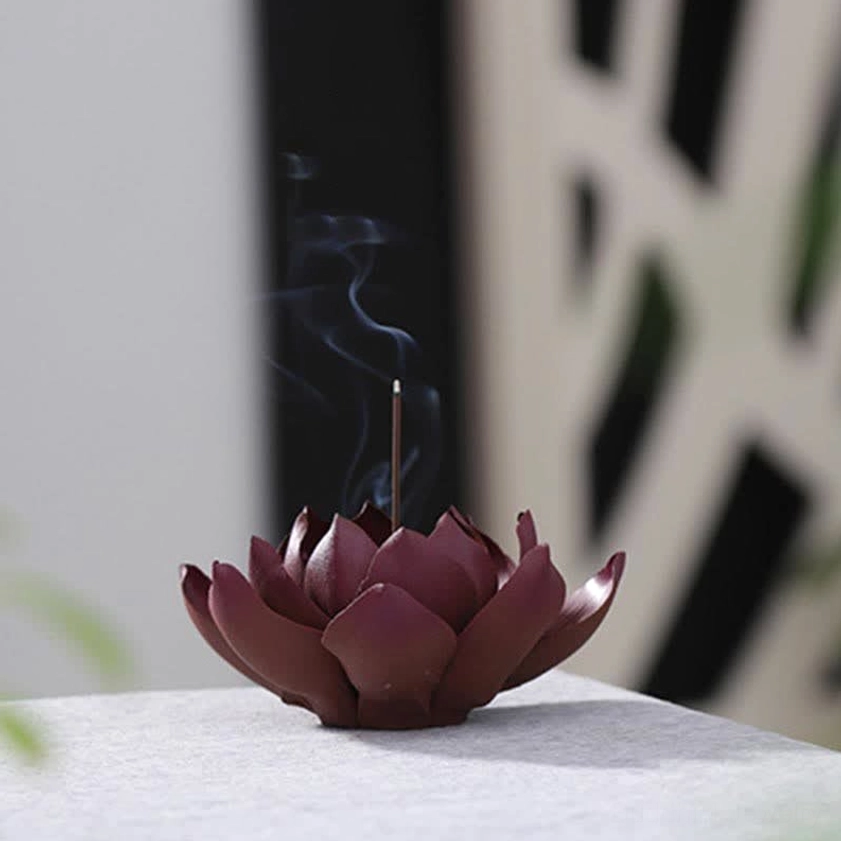 Indoor meditation setup: lotus purple clay incense burner with smoking incense stick on dark wooden backdrop