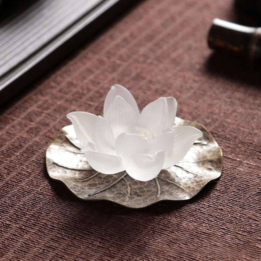 White lotus incense burner with metallic leaf tray flat lay on textured fabric surface
