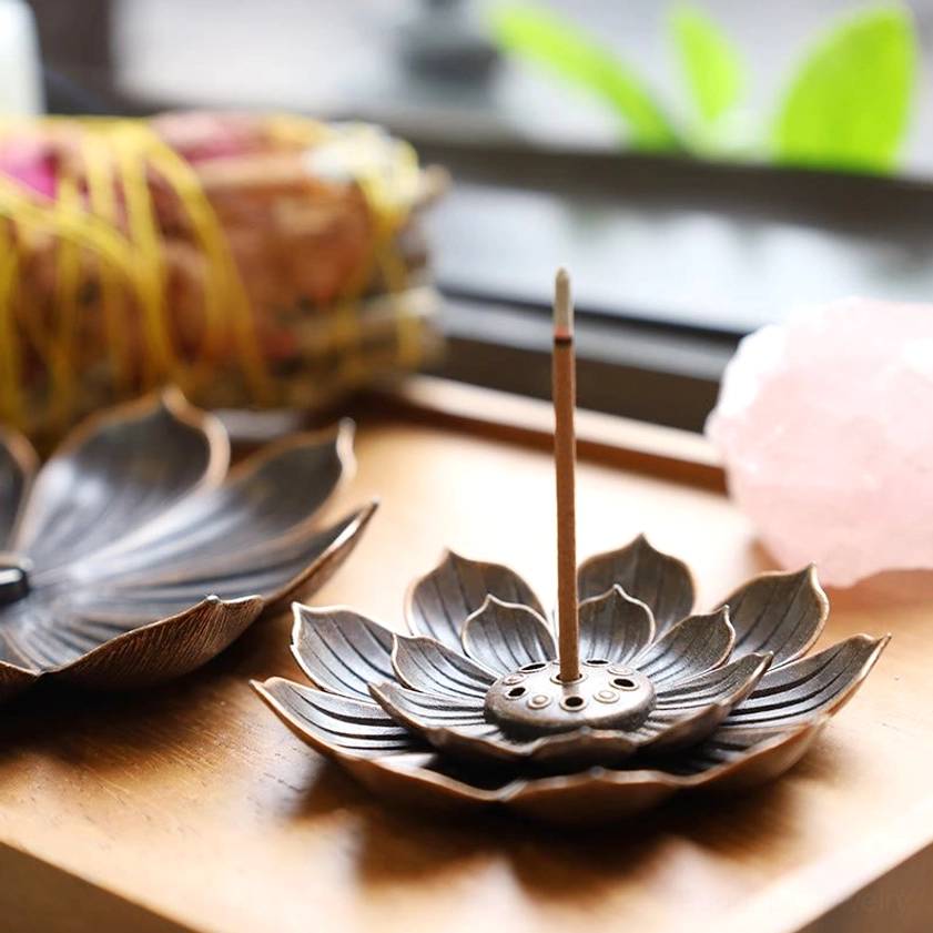 Lotus incense holder with burning incense on wooden tray styled with complementary home décor and spiritual items