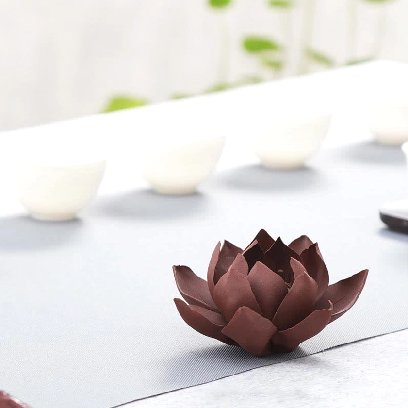 Minimalist tea table display: lotus incense burner with dark maroon matte petals on light gray table mat