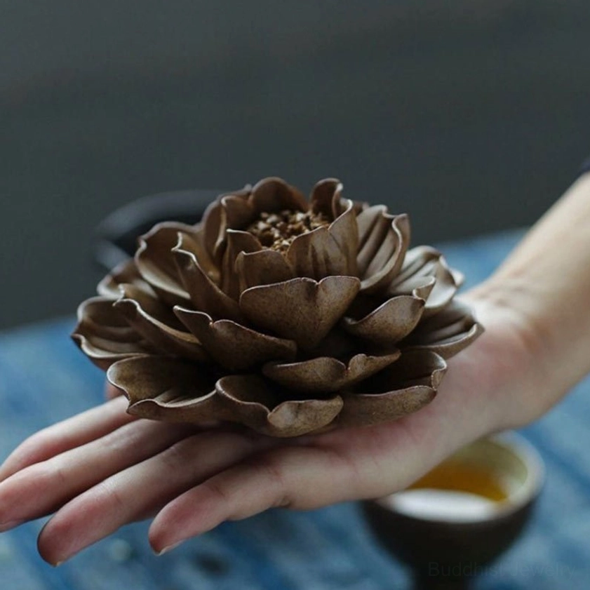 Side profile of ceramic lotus incense holder held in palm showing layered petal design and central incense holes