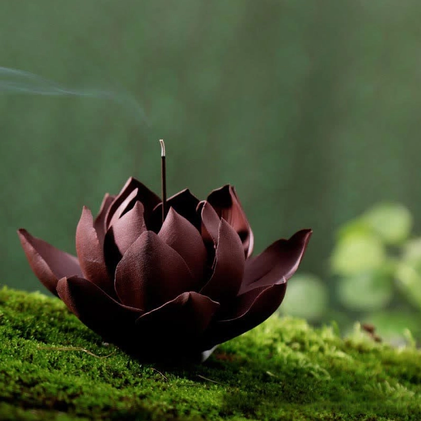 Handcrafted lotus purple clay incense burner with dark maroon layered petals and burning incense stick, side high-angle view
