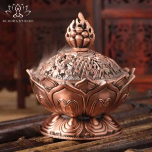 Red bronze Buddhist lotus incense burner with carved lid and flame finial, showing intricate hollow relief patterns and smoking incense