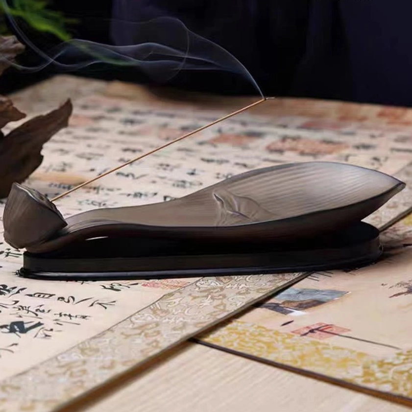 Side low angle of burning lotus pod incense holder with curling aromatic smoke and embossed lotus pattern