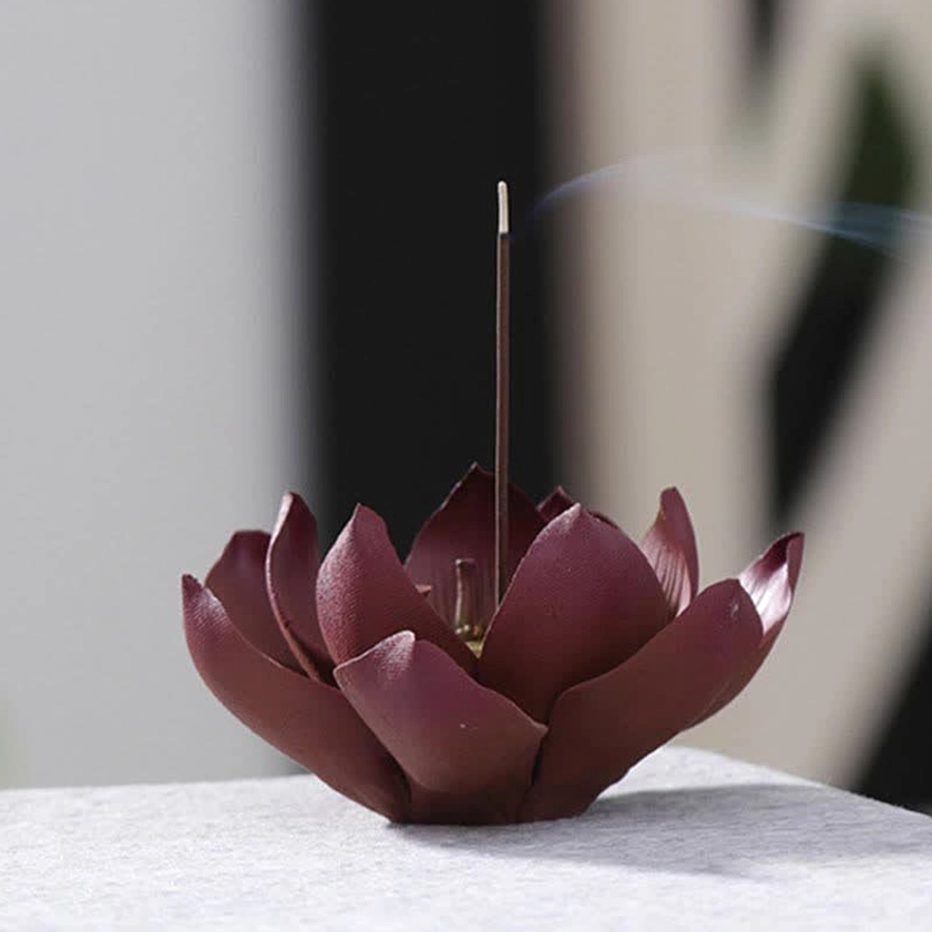 Three-quarter view of lotus purple clay incense burner with visible incense ash and dark tabletop setting