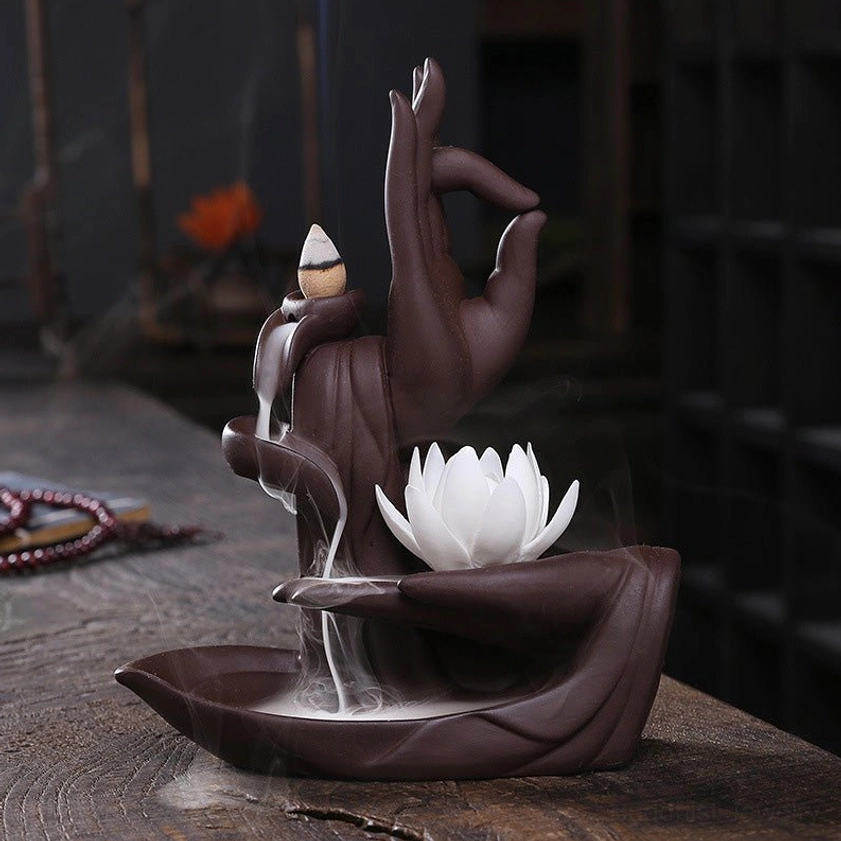 Buddhist lotus incense burner featuring white artificial lotus crown, ceramic base, and dramatic backflow smoke waterfall effect