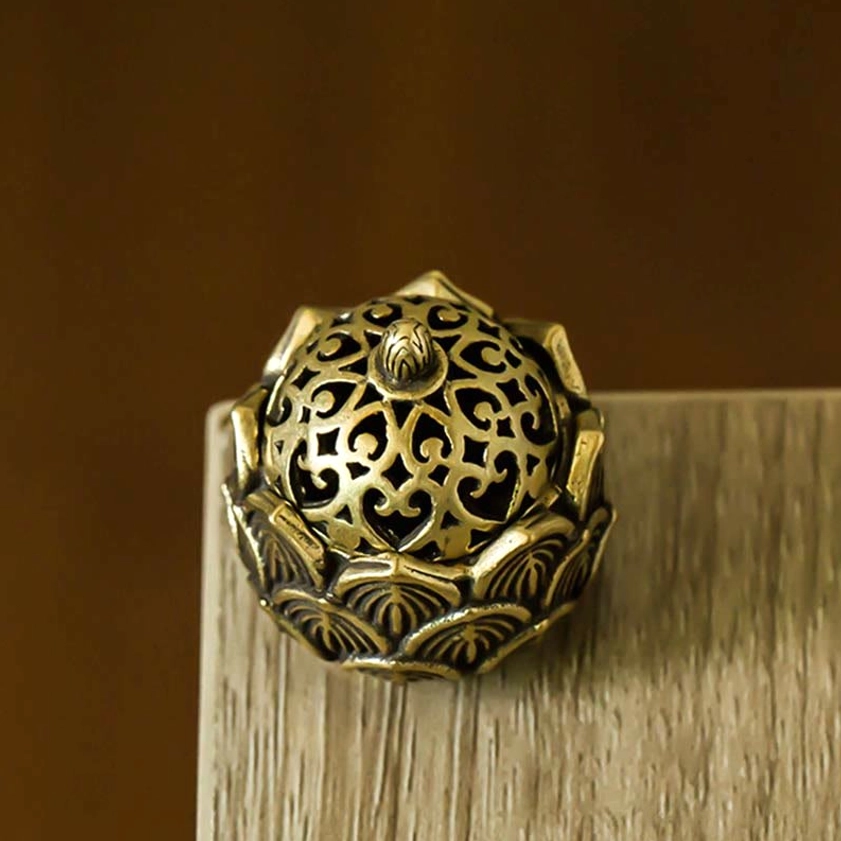Full eye-level view of assembled mini lotus incense burner with ornate hollow floral carved lid on wooden table