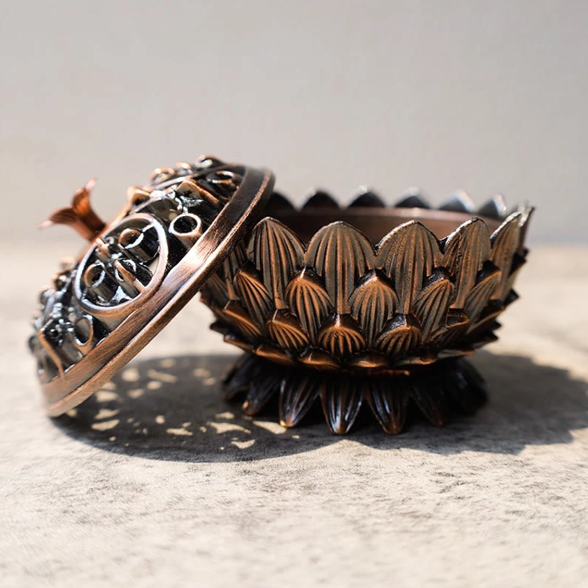 Dark bronze lotus incense holder with tilted detachable lid showing lotus petal body and small decorative finial