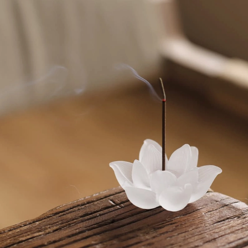 Lotus crystal glass incense holder burning with rising smoke on wooden desk meditation space