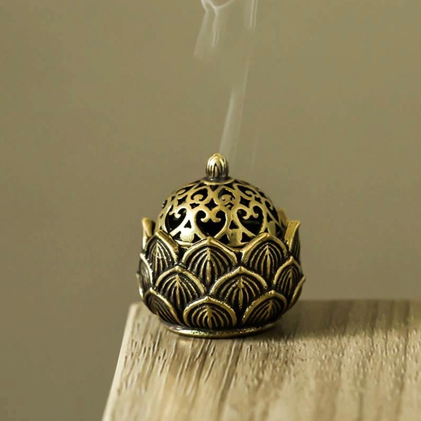 Eye-level close-up of antique brass lotus incense burner fully assembled with rising aromatic incense smoke