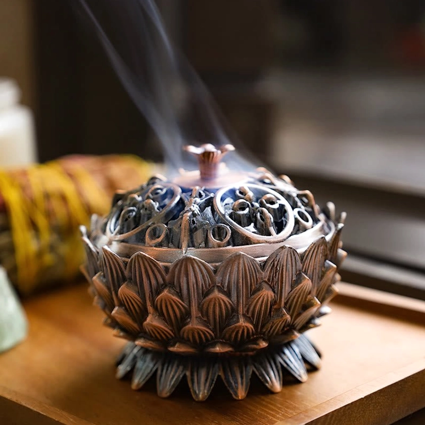 Red bronze lotus incense holder with visible smoke rising, displayed on wooden spiritual tray with ritual supplies