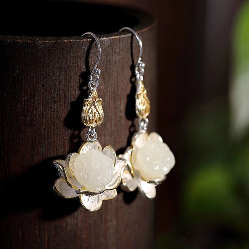 Buddhist lotus drop earrings with mixed metal finish displayed in dark wooden container showing intricate silver and gold details