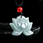 Carved lotus jade pendant necklace with red accent bead on black cord, front overhead view against dark backdrop