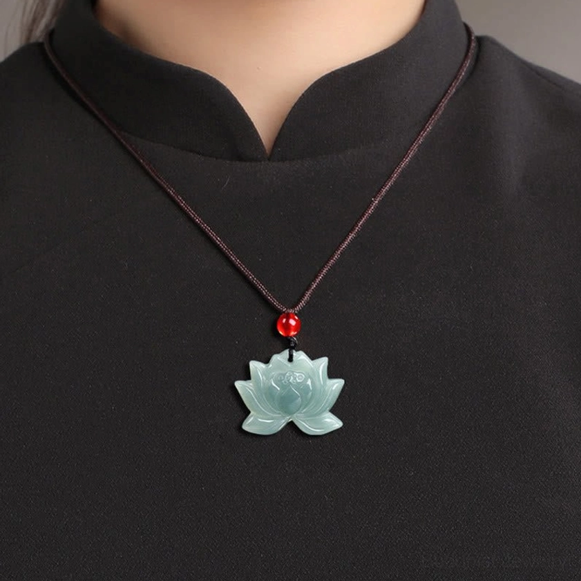 Lotus jade Buddhist necklace worn on brown cord around neck showing carved pendant with red bead styling