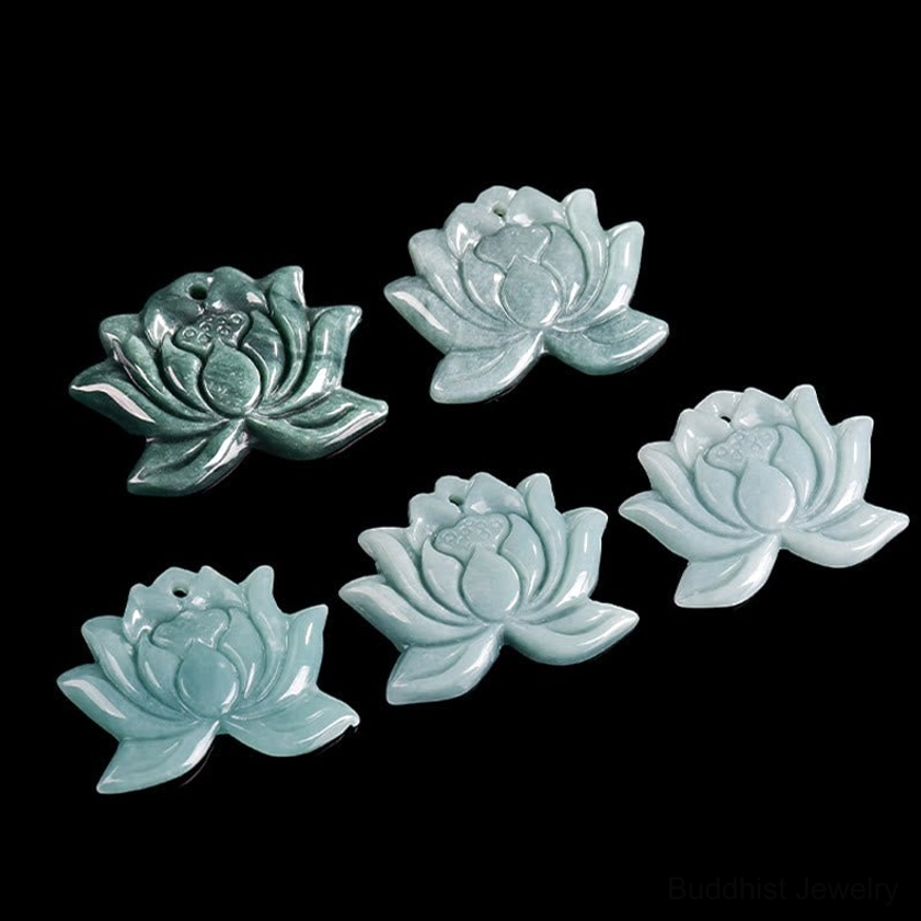 Multiple hand-carved lotus jade pendants in assorted green tones showing natural color variations, flat lay composition