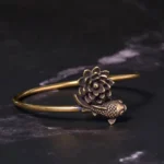 Lotus koi copper brass open cuff bangle bracelet with embossed lotus flower and koi fish charm, displayed on dark marble surface showing side top view