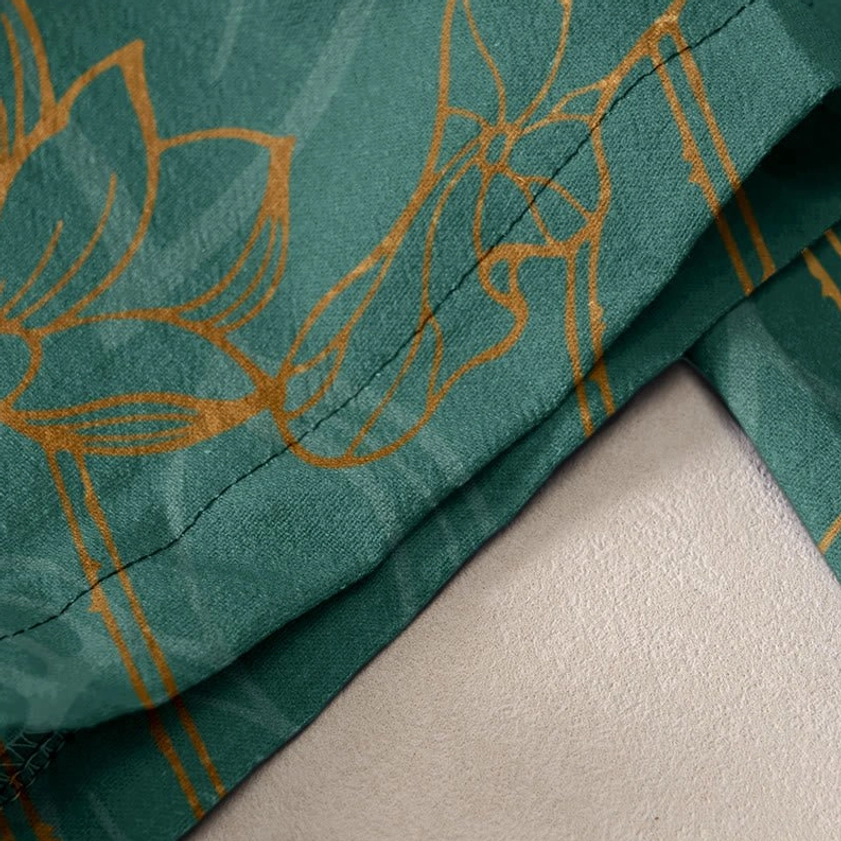 Side view close-up of dark green cotton fabric texture with gold lotus and koi fish print pattern detail