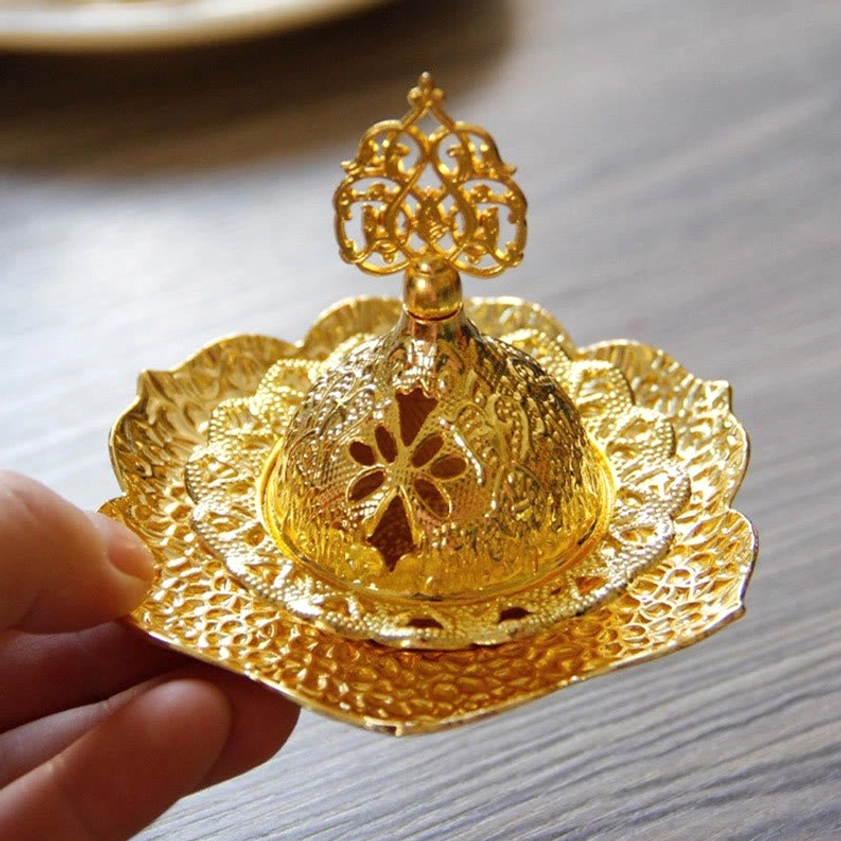 Hand-held alloy incense burner front angle showing symmetric floral hollow cuts and textured metal surface