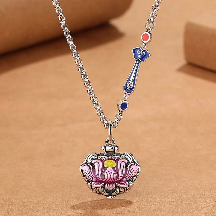 Front view of lotus lock pendant necklace featuring silver chain with decorative cloud charms and blue enamel accents on kraft paper background
