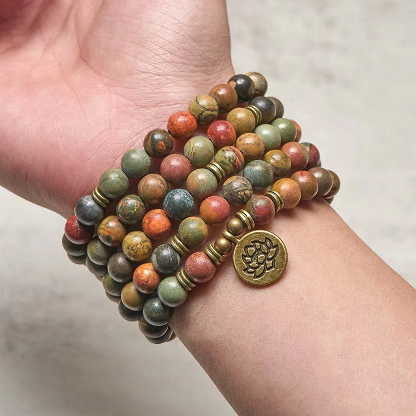 Red turquoise mala bracelet wrapped multiple times on wrist with brass lotus charm