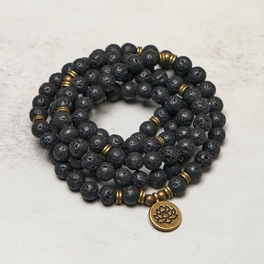 Buddhist prayer mala necklace with hanging bronze lotus pendant and metal accent beads on neutral background