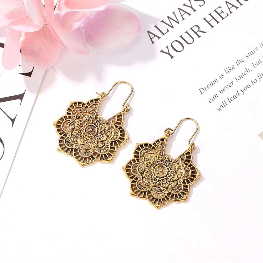 Antique gold lotus mandala drop earrings with hand-engraved texture, flat lay styling with pink flower and spiritual card