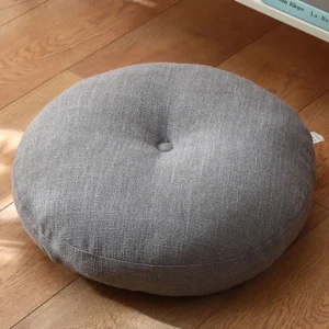 Dark gray linen lotus meditation seat cushion with central button tufting, overhead view on wooden floor