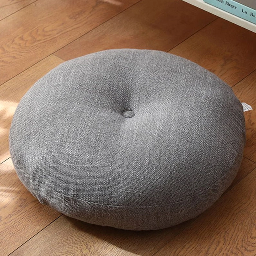 Dark gray linen lotus meditation seat cushion with central button tufting, overhead view on wooden floor