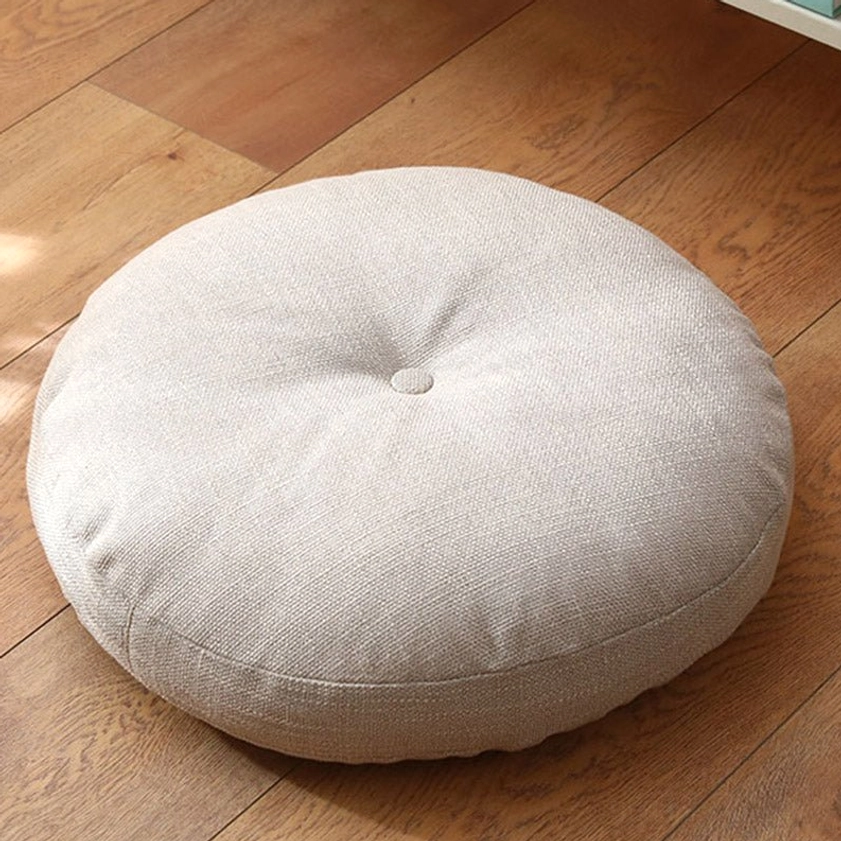 Light beige linen lotus meditation floor cushion with central button tufting on wooden floor