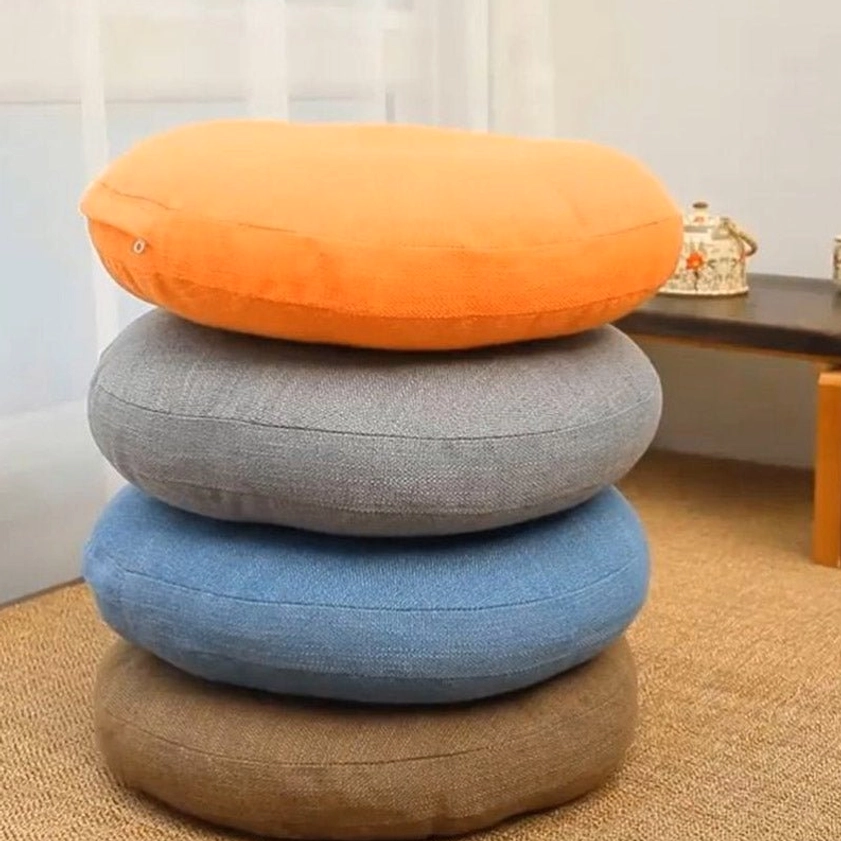 Stacked linen meditation floor cushions in orange, gray, blue and brown arranged in home corner