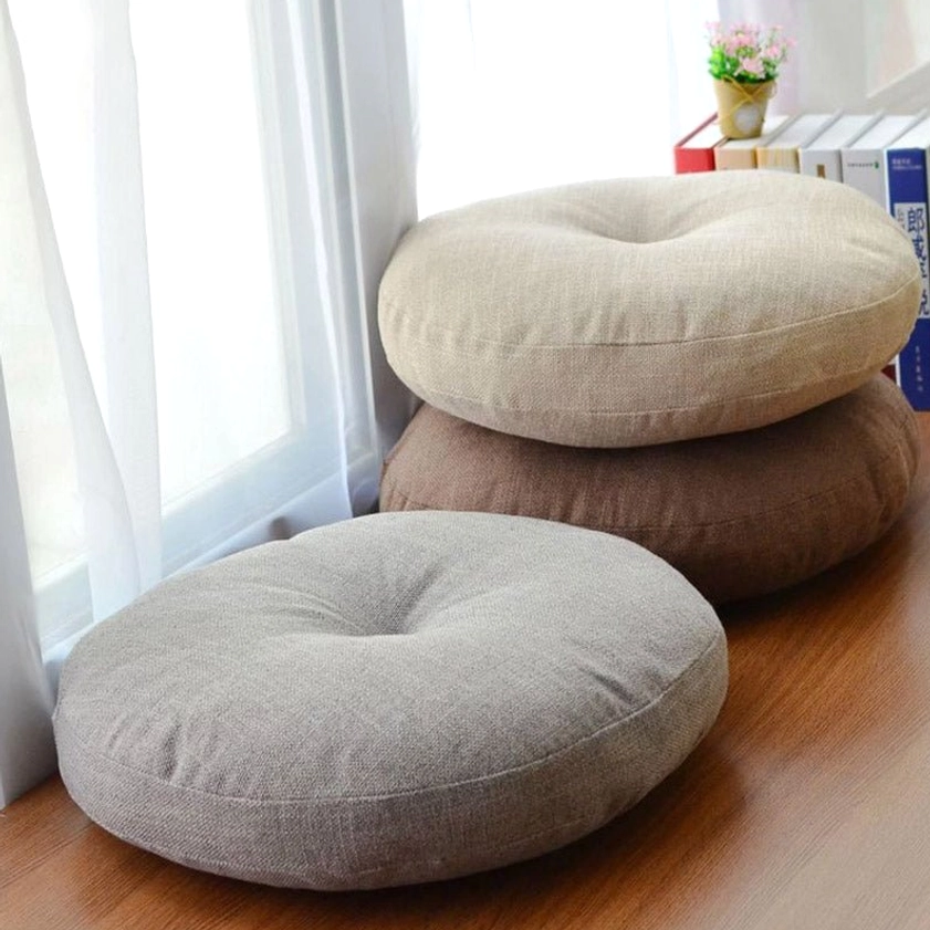 Stacked round meditation seat cushions in neutral tones beside window, linen floor cushions