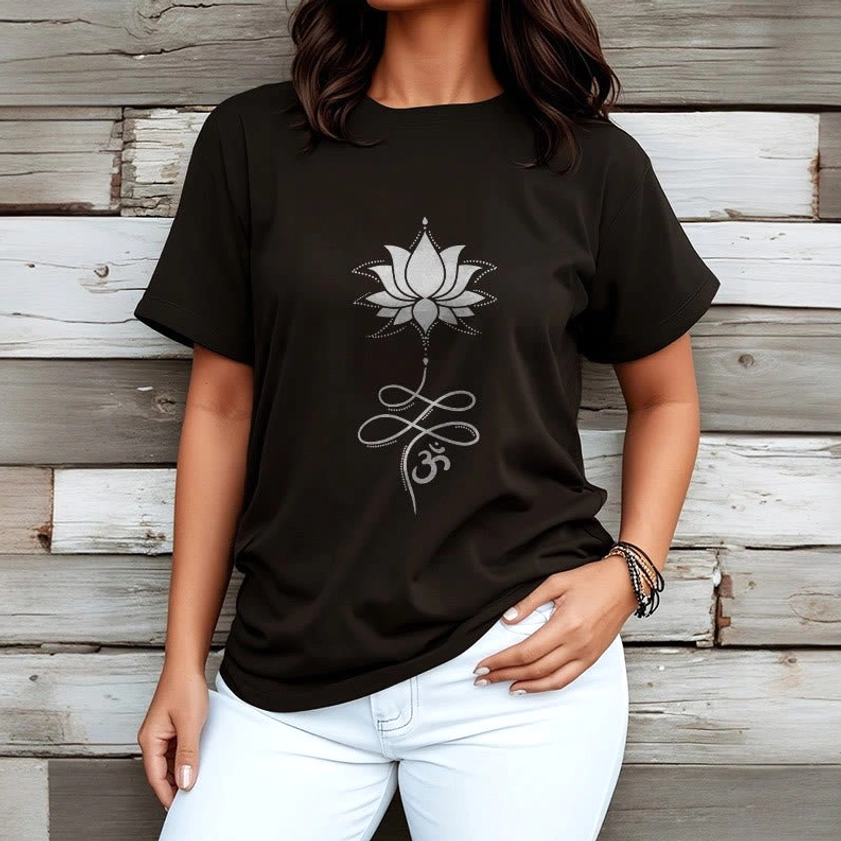 Female model wearing black lotus om print Buddhist cotton tee with white jeans, wooden plank background, casual styling