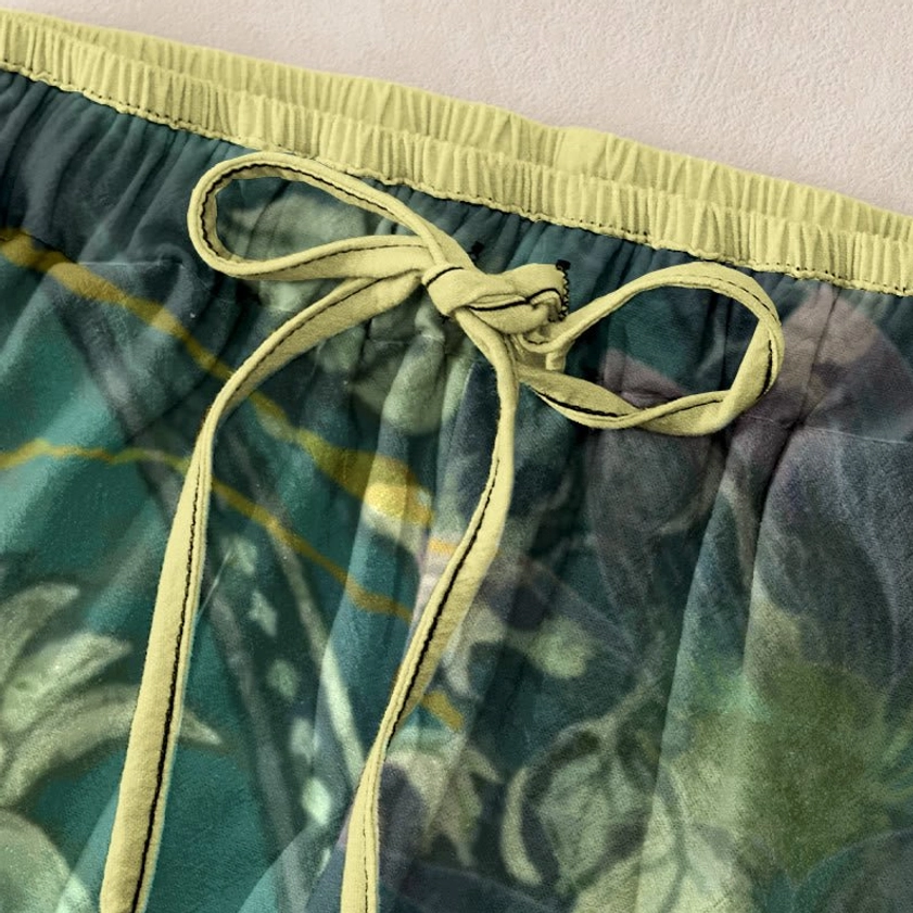 Close-up detail of elastic waistband with yellow drawstring and contrast stitching on lotus pattern pants