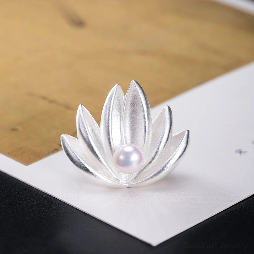 Angled front view of handcrafted sterling silver lotus pearl brooch on mixed paper background showcasing minimalist elegant design