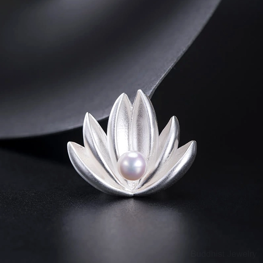 Low angled front view of handmade lotus pearl brooch showing symmetric layered silver petals on black studio backdrop