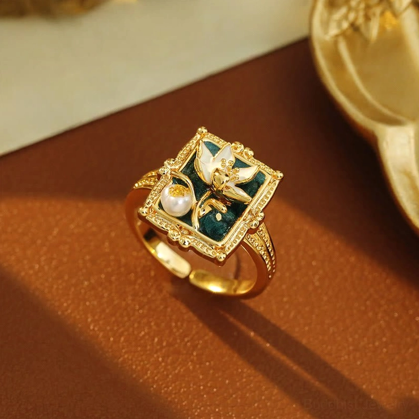 Vintage lotus pearl copper ring adjustable - elegant gilded frame with white pearl and dark enamel lotus detail on brown leather desktop